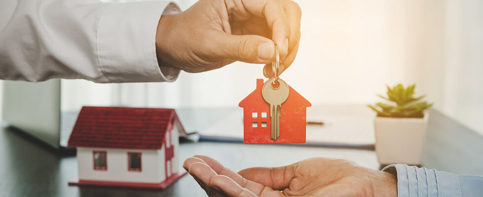 real estate agent holding house key to his client after signing contract, concept for business loan, investment mortgage, real estate, moving home or renting property.